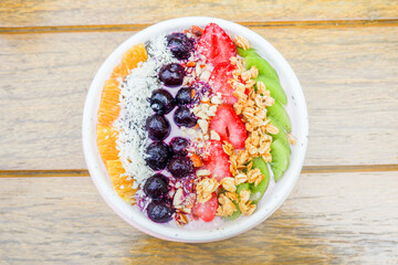 Healthy and colorful Breakfast Acai smoothie bowl with blueberries,kiwi fruit,chia seeds and coconut flakes on wooden background,close-up, top view, space for text.