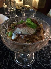 A gourmet appetizer featuring tender mushrooms and a soft-cooked egg, garnished with fresh greens, served in an elegant glass dish. Perfect for fine dining and culinary delight enthusiasts.