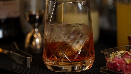 Cropped closeup hand bartender stirring mixed ingredients alcohol liquor syrup into mixing glass with cube ice prepared Old fashioned cocktail tasting showcasing nightlife mixology at bar. Vinosity.