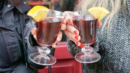 Two hot wine glasses garnished with orange slices, raised in a toast to celebrate a special occasion, capturing a joyful moment.