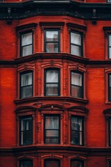 Fototapeta premium Vintage urban architecture featuring a red-brick building facade with large windows in a historic district during daylight hours