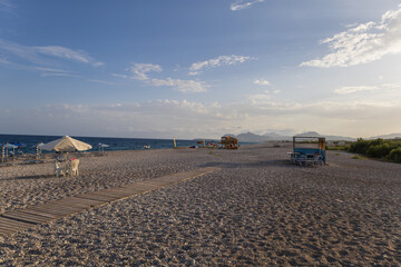 Beach by the sea on the island of Rhodes in Greece. Parasols and sunbeds on the beach