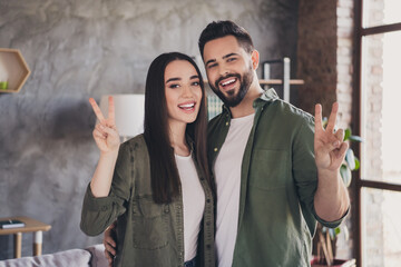 Photo of young attractive charming married people buy flat moving relocation cosy modern loft interior apartment indoors v-sign