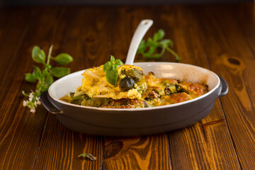 cauliflower and brussels sprouts casserole with cheese, in a ceramic dish on a wooden table