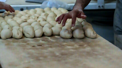Baker shaping dough portions on a wooden surface