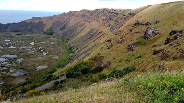 Camera pans over the rano kau volcano crater with the pacific ocean in the background on easter island