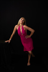 Naklejka premium Beautiful caucasian woman standing in red dress posing for photo. Isolated on black background in studio in Salvador city, Bahia.