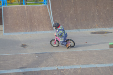 Fototapeta premium a child, a boy riding a running bike, a bicycle on a sports field, a photo without filters