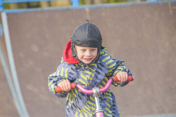 a child, a boy riding a running bike, a bicycle on a sports field, a photo without filters