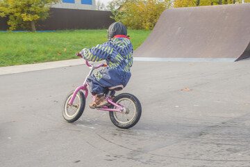 a child, a boy riding a running bike, a bicycle on a sports field, a photo without filters