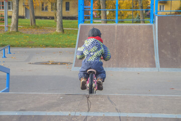 a child, a boy riding a running bike, a bicycle on a sports field, a photo without filters