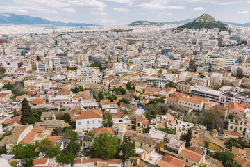 Obraz premium Aerial view of Athens with blue ocean and skies in the back ground. The view showcases historical buildings of the city with green domes and colourful facades. 
