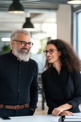 Fototapeta premium A man and a woman are smiling at each other in a room. The man is wearing glasses and the woman is wearing a black shirt