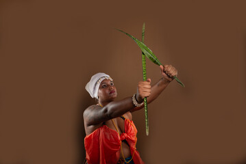 Woman in traditional Candomble clothing, holding the Espada de Sao Jorge plant and posing for a...