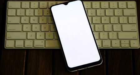 Celular com fundo liso branco em cima de teclado - Cell phone with a plain white background on top...
