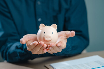 warranty, financial, loan, rich, finance, wealth, tax, safe, savings, piggy bank. A man is holding a piggy bank in his hand.
