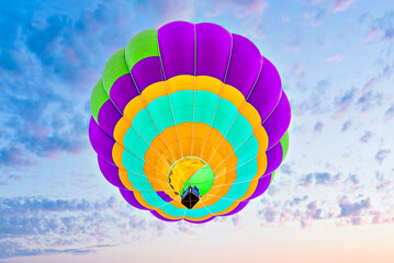 Colorful hot air balloon flying over blue sky with white clouds	