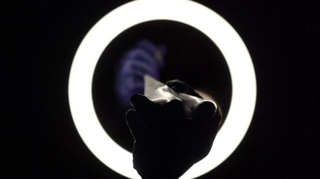 female hands in blue rubber latex gloves open, unfold, stretch and test the strength of a condom close-up on a black background. protection against sexually transmitted diseases and contraception