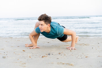 Sporty woman is engaged in animal flow gymnastics outdoors on sea beach. Female trains with Animal...