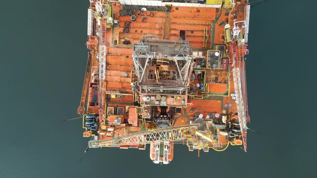 from offshore oil rig drilling platform parked estuary role energy production overflight engineering top down birdseye aerial drone view operational orders 