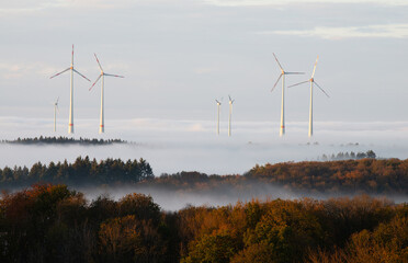 Windmills in forest with fog, transformation to renewable sustainable energy, electricity...