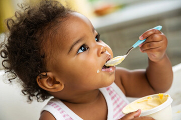 portrait of mulatto baby girl eats yogurt