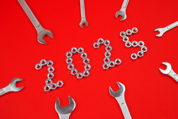 Number 2025 by metal nuts and wrenches on a red background. 2025 year