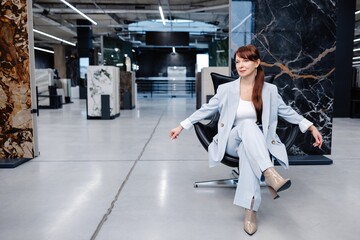 Woman in light blue suit posing in a modern office space