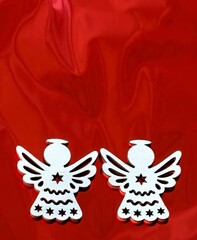 two beautiful Christmas angels wooden decoration on shiny red background