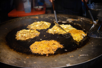 A person is cooking Fried oysters food in a pan that is shaped like a circle. The food is being cooked in oil and he is fried