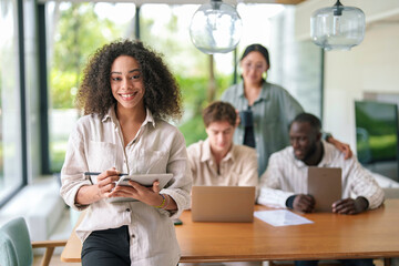 A lively African American woman engages with a digital tablet, her cheerful demeanor evident....
