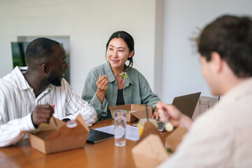 A group of young adult business professionals of diverse ethnic backgrounds enjoys a casual meal...