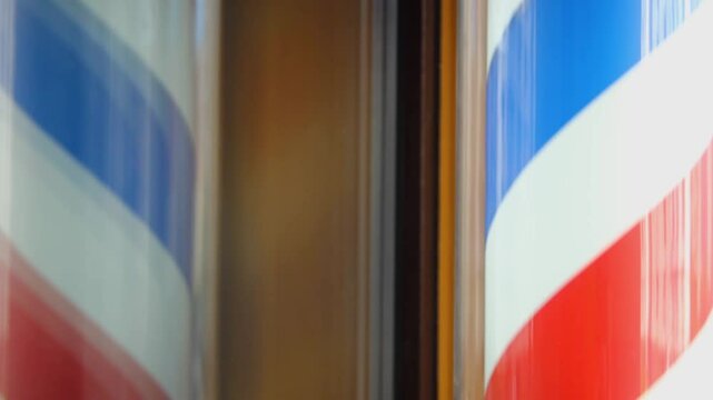 the barber's sign, Barber's pole, hangs on the wall at the entrance to the barber's shop. The three-color ribbon is spun in a plastic glass tube. Red blue white closeup