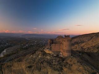 Fototapeta premium Fantasy fortress at sunset in the mountains of Georgia - Aerial Drone View,