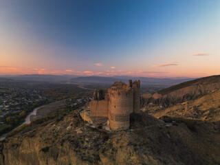 Obraz premium Fantasy fortress at sunset in the mountains of Georgia - Aerial Drone View,