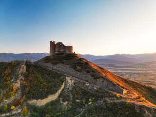 Obraz premium Fantasy breathtaking castle on top of mountain at sunset in Georgia Ksani