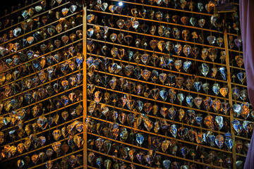 A Golden bodhi leaf hanging from a metal frame. The ornaments are of various shapes and sizes, and they are all hanging in a row.
