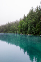 Morning fog over a beautiful lake surrounded by a pine forest at the foot of the mountains. Stock photography