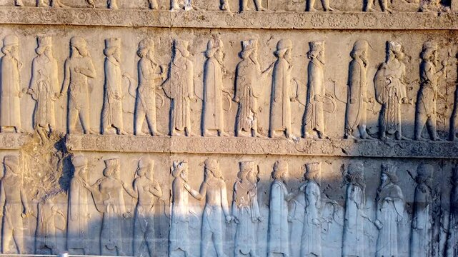 Sunlight reveals details of soldiers and a lion attacking a mythical creature carved into a stone wall