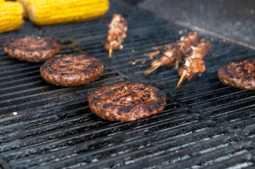 Sizzling Burgers and Skewers on a Grill with Corn
