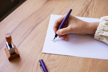 Woman Handwriting Letter with Purple Pen on White Paper