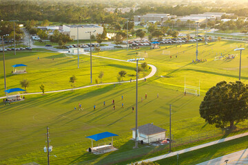 School children playing soccer game during physical exercise on school stadium at sunset. Active way of life concept