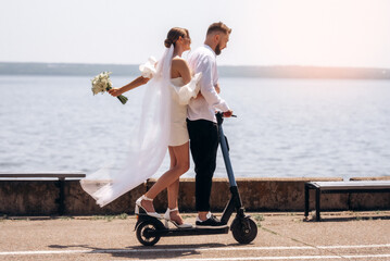 Groom and bride using electric scooter together. Newlyweds couple riding electric scooter.