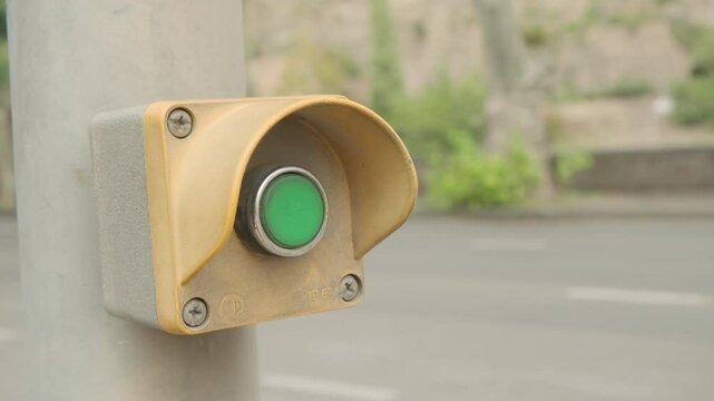 Pedestrian pressing button to cross road with car traffic.