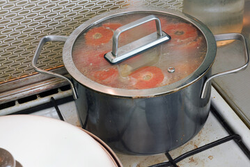 stuffed tomatoes, with forcemeat with rice and greens, stewed on a stove, in exquisite pot with clear glass lid