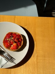 Strawberry tart on a plate with natural light and wooden table