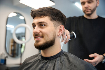 Fototapeta premium Professional groomer uses big brush to apply white powder