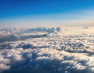 A stunning aerial view shows fluffy white clouds floating above Earth's landscape against a deep blue sky.