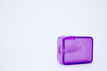 A detailed close-up shot of a purple pencil sharpener on a white background, highlighting its vibrant color and sharp edges. Ideal for collections focused on office supplies and stationery.