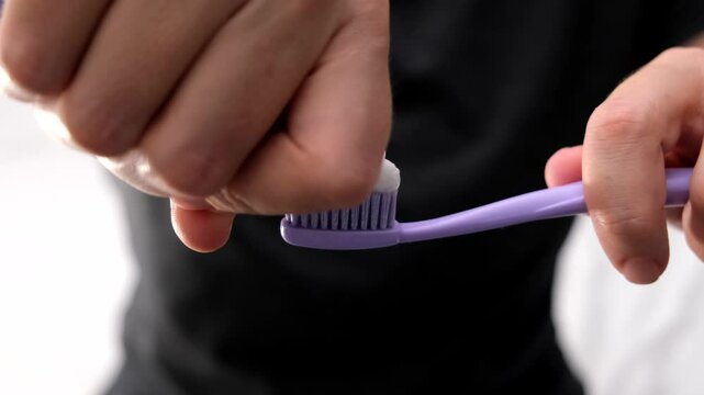 Woman squeezing toothpaste on a toothbrush close up